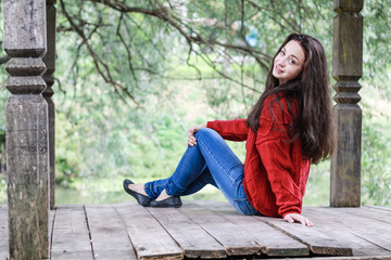 Young girl laughing sitting on a wooden floor in the park.