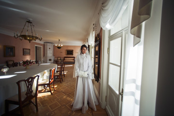 Fototapeta na wymiar Beautiful bride poses in a winter coat inside the old house
