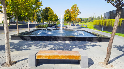 Скамейка на фоне фонтана осенью в окружении деревьев в сквере © bmarya83