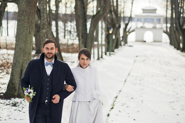 Road covered with snow lies behind walking wedding couple
