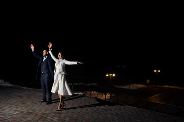 Merry wedding couple poses outside in the night