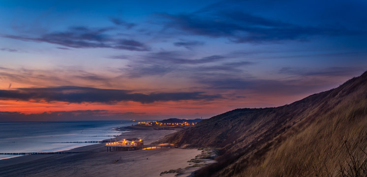 Beautiful sunset in the dunes at the beach with a beach club and ships