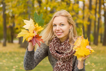 Young, beautiful, gentle woman in the park enjoying autumn when leaves become colorful.