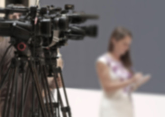 Abstract blurred background of video cameras recording in press conference.