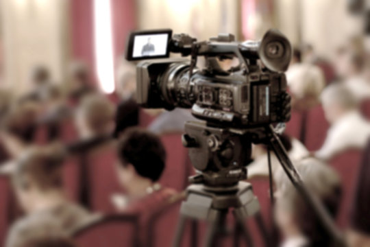 Abstract blurred background of video cameras recording in press conference.