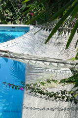 Hammock over swimming pool and its shadow in it 