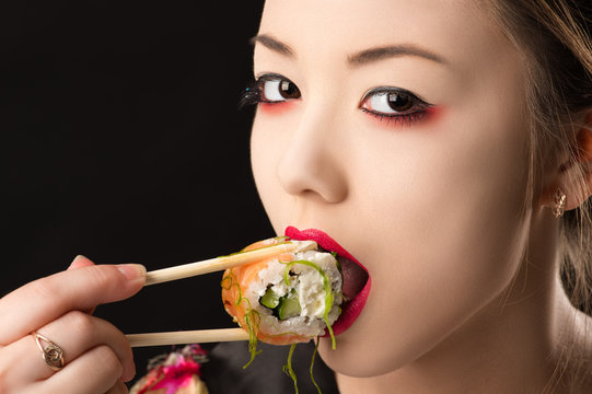 beautiful korean teenager girl with bright makeup eating sushi