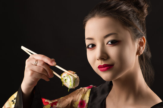beautiful girl with bright makeup eating sushi closeup