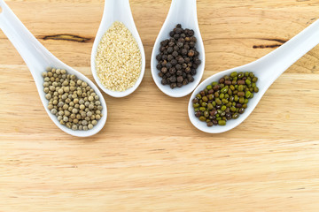 Green bean , white sesame ,black and white pepper in white ceramic spoon