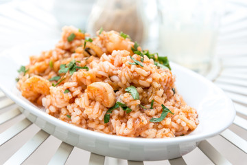 Tasty risotto with Shrimp, fresh herbs vegetables on a white pla