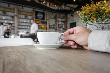 businessman hand holds a cup of coffee in a cafe with space for