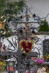 Fototapeta na wymiar Schmiedeeisernes Grabkreuz mit Herz aus Rosen geschmückt