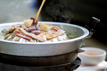 Grilled liver pork and bacon on the hot pan with chopsticks,  Grilling sliced pork and meat on hot pan asian style / selective focus