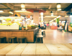 Defocused or blurred photo of food court montage with wood table top use for background.