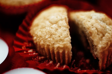 Soft focus. Muffins in a red wrapper on red knitted sweater, red candles and bokeh. Christmas atmosphere