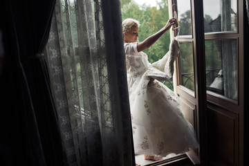 Bride is holding a wedding dress on the balcony