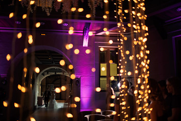 Newlyweds are walking to the hall with many lights