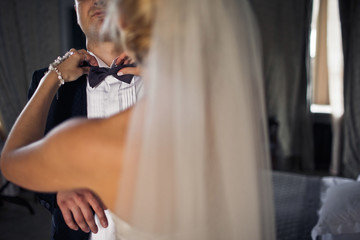 Obraz na płótnie Canvas Bride is holding a groom's bow-tie