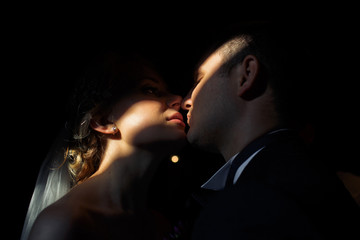 Romantic kiss of the newlyweds in the dark room