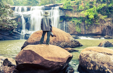 The man standing with camera at Tad Huang Waterfall,become the murder line between Thai-Laos at at Phu Suan Sai National Park,Loei Province.Processed in vintage style,soft focus.