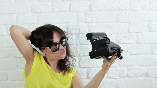 Young happy woman in sunglasses taking selfie with instant camera 
