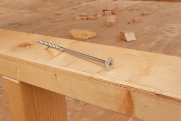 Screws and nails to build a wooden house. Joining wooden beams. Construction works.
