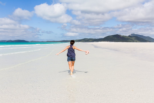 Happy running woman on beautiful beach in the Whitsunday Islands in Australia
