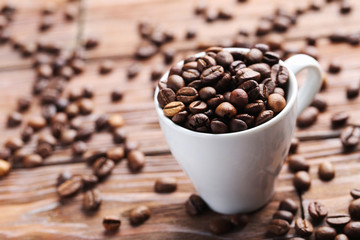 Roasted coffee beans in cup on a brown wooden table