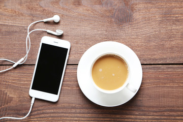 Cup of coffee and smarphone on a brown wooden table
