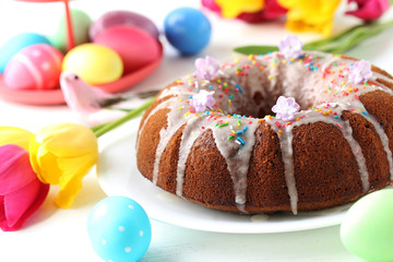 Easter eggs with cake on a white wooden table
