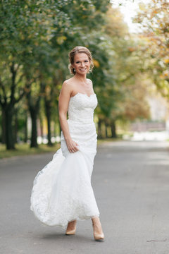 Happy bride in the wedding dress in the park
