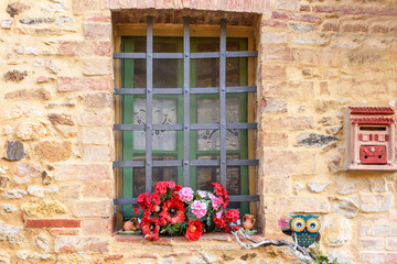 window with iron grating decorated with flowers and terracotta mailbox