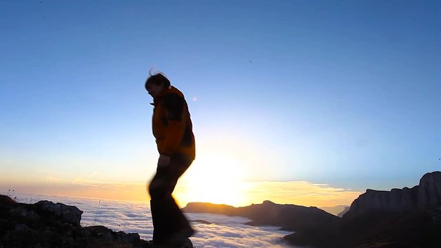 Happy Winning Success Woman at Sunset or Sunrise Standing Elated with Arms Raised up Above Her Head in Celebration of Having Reached Mountain Top Summit Goal during Hiking Travel Trek
