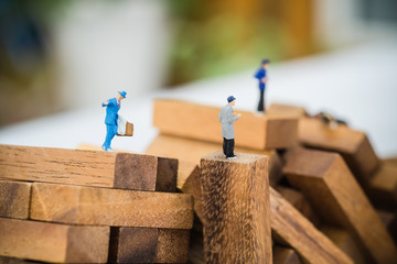 Miniature businessman on wooden block or obstacles among competi