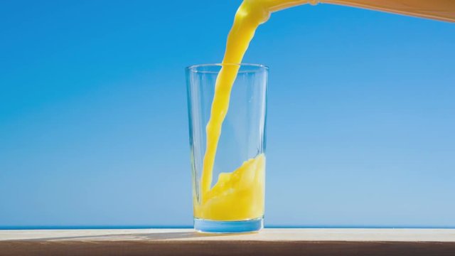 pouring a glass of orange juice creating splash