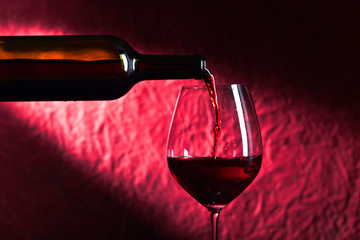 Bottle and glass of red wine on a dark  background