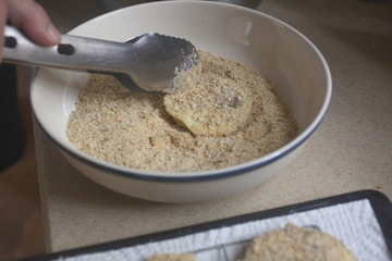 Coating sliced eggplant with breadcrumbs.