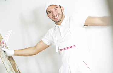 Obraz premium Young man painting windows. Happy young painter holding paint brush and repairing windows.