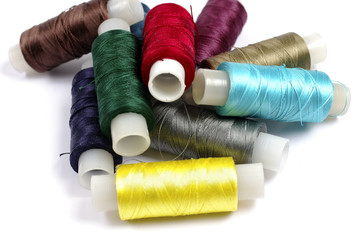Spools of multicolored silk threads on white background