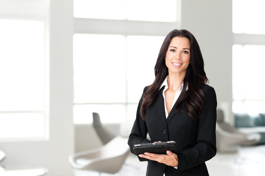 Attractive businesswoman real estate agent property manager with digital tablet in modern office waiting room lobby