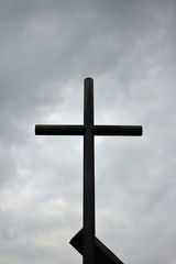 Black metal cross under a cloudy sky