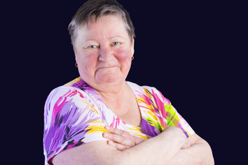 Portrait of disappointed senior woman with grimacein photo studio isolated on dark blue background