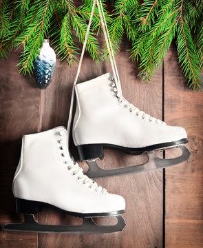 Christmas decoration. Skates and fir branch on wooden background.