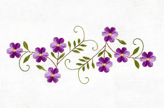 Embroidered satin stitch,melange thread purple flowers with leaves on cotton cloth
