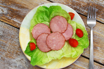 Slices of traditional Polish smoked sausage on green lettuce
