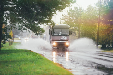 Lorry on wet road rides through a puddle