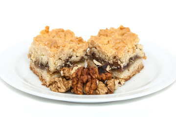 Fruitcake with jam and kernels of walnuts on a white plate
