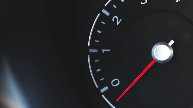 Color close up footage of a car's tachometer idling and engine stopping.