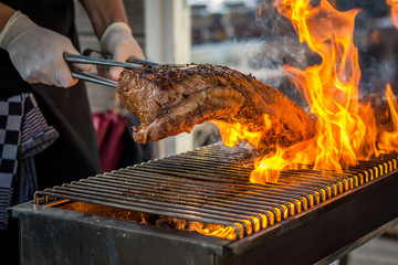 Grilling entrecote on a barbecue with fire  - obrazy, fototapety, plakaty