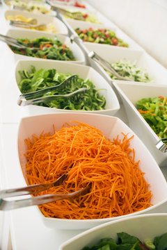 Close-up, soft focus salad bar with a variety of fresh vegetables. Colorful organic raw slice of lettuce, carrots, rukula, cucumber and pecans. Healthy eating food. (selective focus)